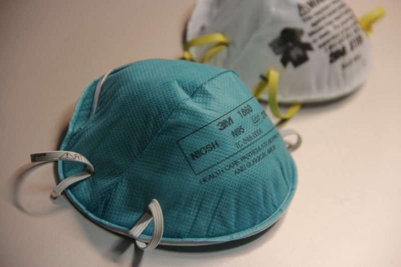 Two N95 respirators resting on a table, one teal and one white